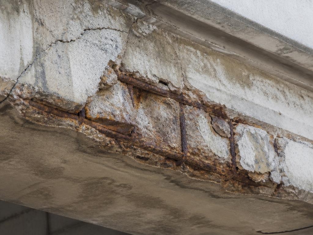 Viga de concreto armado com fissuras e armadura corroída exposta